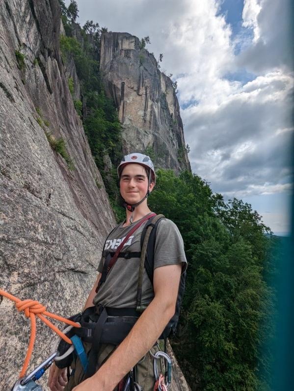 College student wearing a helmet and harness at the edge of a cliff